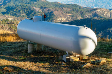 Metal round propane or natural gas tank in afternoon sun and shade on top of mountain or summit with...