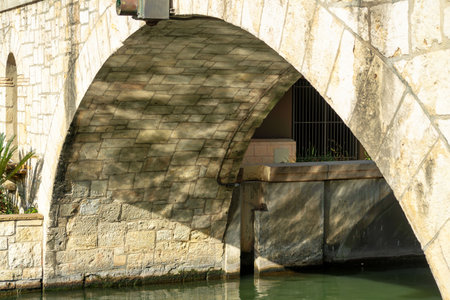 Canal archway or bridge beneath pedestrian walkway and path made of stone and rock facade or exterior with water belowの写真素材