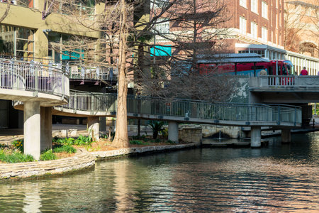 Canal in san antonio texas with pedestrian walkway and sidewalk and bridge for bus and traffic over river or waterwayの写真素材