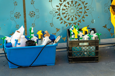 Cleaning supplies in blue and black bucket with spray bottles and rags to wipe clean viruses and keep things tidy. On floor with mop and broom for sanitation and maintenance purposes.の写真素材