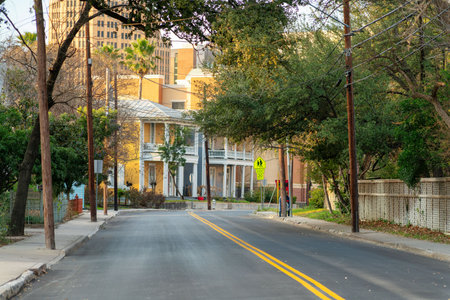 City streets in downtown san antonio residential historic districts near alimo with house and homes and asphalt yellow double lines. Late afternoon shade with street lined with trees in suburban area.の写真素材