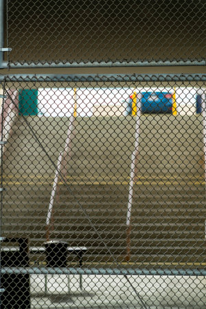 School stairs in a courtyard with visible tables and steps hand rails in late afternoon shade in city neighborhoods. Chain link fence in downtown area closed off place with industrial background.の写真素材
