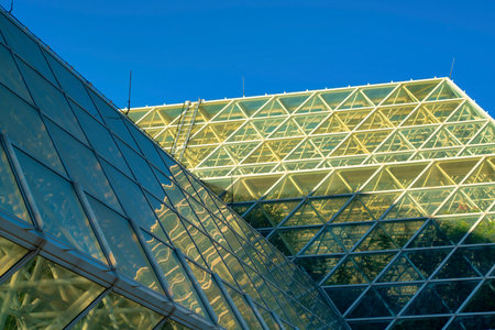 Green house with metal fastenings and girders with glass pannels in geometric fashion with ladders and steps on exterior biodome. Used for cultivating plants and creating natural environments indoors.の写真素材