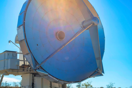 Satelite dish with sun flare on metal top with blue sky background in science center or laboratory....