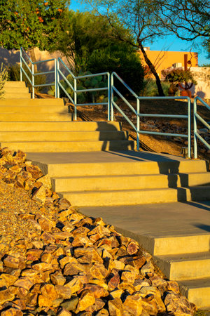 Cement stairway with gray metal handrail and rock or stone desert landscaping with platforms and steps. In park or outdoor area of town in neighborhood or outdoors part of suburbia.の写真素材