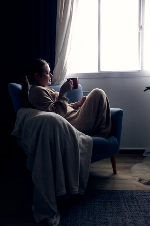 woman sitting on the sofa and drinking hot beverageの写真素材