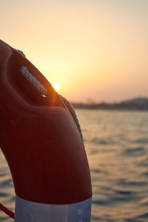life saving floating device on a boat with the sunset in the background. gold and red theme.の写真素材