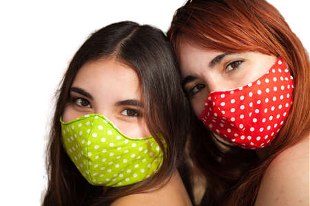 Two female friends mother and daughter with colorful face masks isolated on white background protect themselves from covid-19 coronavirusの写真素材
