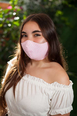 beautiful teenage girl with pink surgical mask with polka dots protects herself from the covid-19 coronavirus.の写真素材
