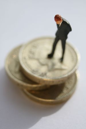 Miniature businessman standing on coinsの写真素材