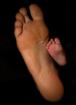 parent dad foot with baby newborn toddler feetの写真素材