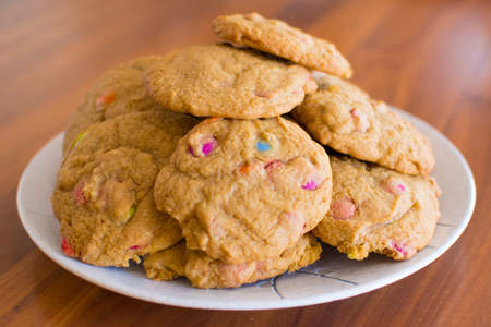 A decorative blue plate loaded with delicious, fresh home made chocolate chip cookies on a wooden...