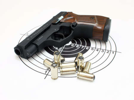 The close up of a pistol a target and cartridges is isolated on a white background
