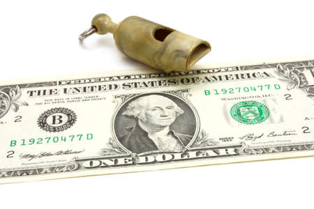 Simple plastic whistle lies near to dollar a denomination on a white background