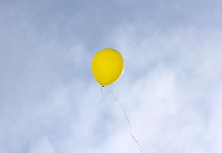 Yellow balloon flying on a blue sky background.の写真素材