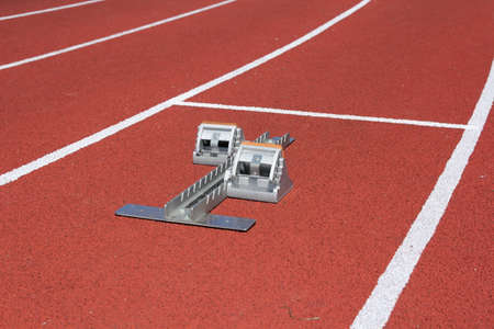 Athletics starting blocks on race red track.