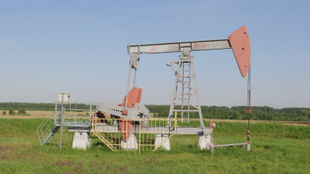 Operating oil and gas well in oil field, profiled against the blue sky.