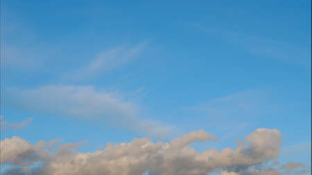 Fluffy clouds float across the blue sky.