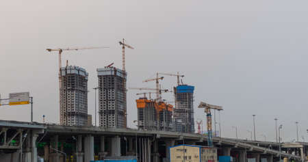 Many of cranes. Tower cranes against blue sky, with clouds.