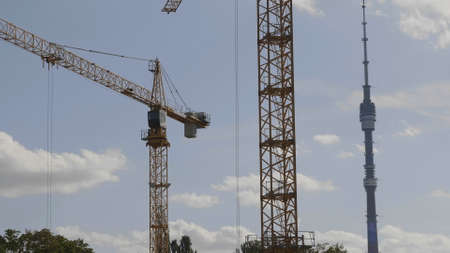 Many of cranes. Tower cranes against blue sky, with clouds.