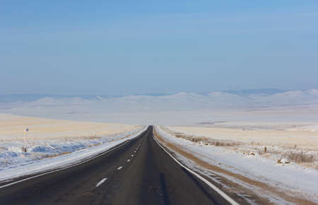 Winter road leaving into distance into the mountains.