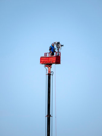 View of a professional camera operator on top of tower for high ground view.