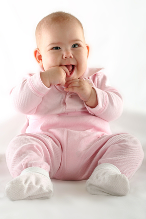 Cute baby girl smiling with thumb in her mouthの写真素材