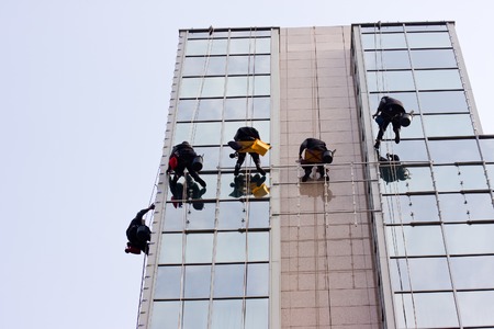 Men cleaning windows on a corporate bouildingのeditorial素材