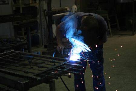 Welder in a workshop making a fence