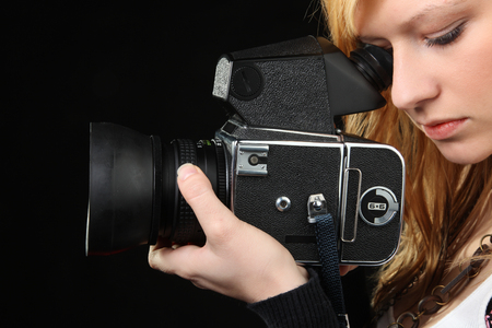 Attractive blonde girl photographing with medium format camera