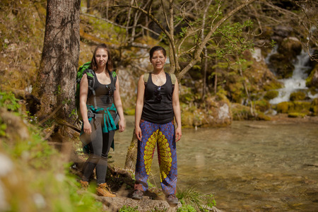 Two Young Women Backpackers Hiking In Beautiful Forest Natureの写真素材