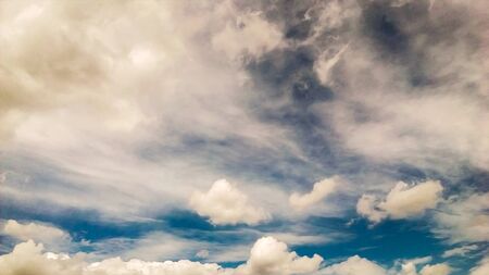 background of the blue sky and some white and grey cloudsの写真素材