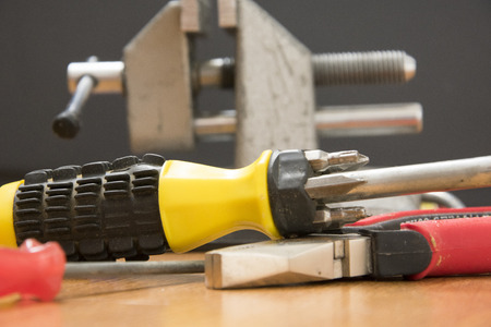 small portable vice screwdriver tools for repair  randomly scattered on the work surface