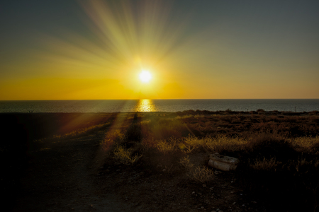 coast line with lighthouse, dune and rare vegetation in the background at sunsetの写真素材