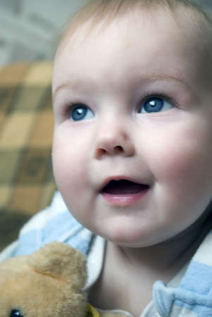 close-up portrait of blue eyes smiling baby boy sitting on the chair with toyの写真素材