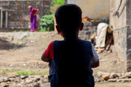 very cute small little boy seated alone on home doorの写真素材