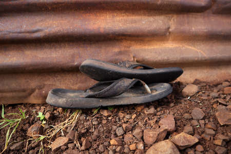 old sandal and sleeper left outside of rusty panelの写真素材