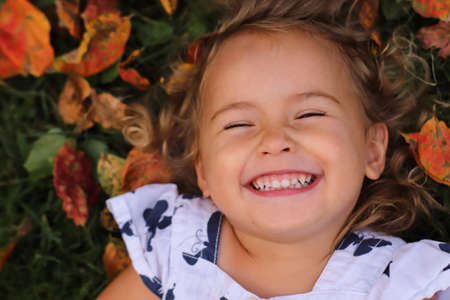 smiling toddler girl lying on the groundの写真素材
