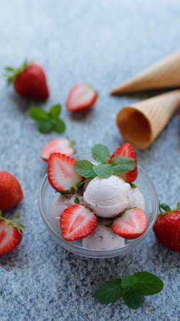 Summer food. Strawberry ice cream with fresh strawberries slices in small bowl served on the table