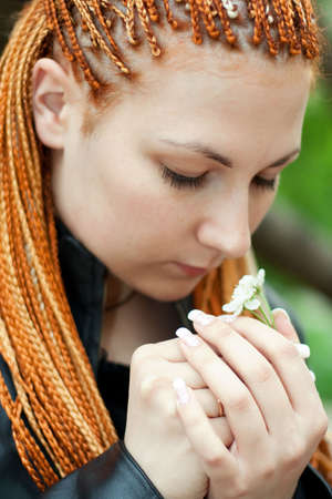 pretty emotional girl with african braids holds a blossoming cherry twigの写真素材