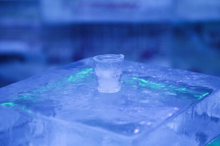 The glass is made of ice for the reception of soft drinks. Neon lights. A bar of ice.