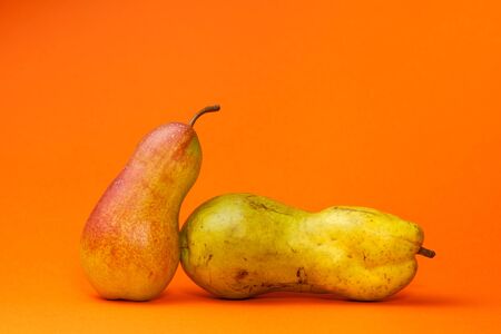 Fashionable ugly organic fruits. Pear on an orange background with copy space for text. Horizontal orientation.の写真素材