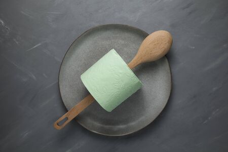 Wooden spoon and toilet roll on a gray plate. Concept on the topic of deficit, madness and panic. Copy space.の写真素材