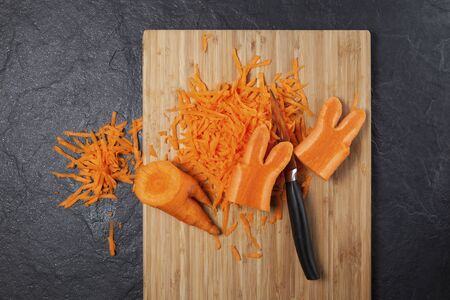 A fashion trend is eating deformed and ugly vegetables. Food waste reduction. Grated carrots on a cutting board. Copy space.の写真素材