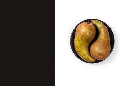 Two ripe pears on a black and white background in the form of a yin yang symbol. Copy space. Horizontal orientation.の写真素材