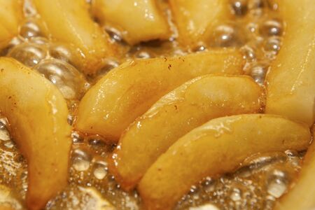 Caramelized sliced pears in honey syrup in a pan, closeup. Delicious dessert for holiday.の写真素材