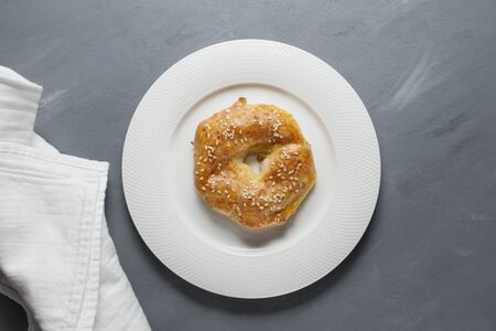 Homemade baking. Delicious gluten free ring with sesame seeds on a white plate. Gray structural background. Top view, close-up. Copy space.の写真素材