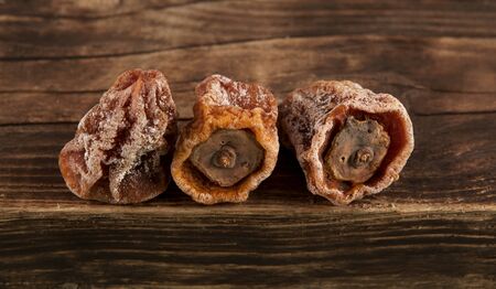 Dried Persimmon (Hoshigaki). Textured wrinkled fruits on a wooden background. Useful sweets.の写真素材