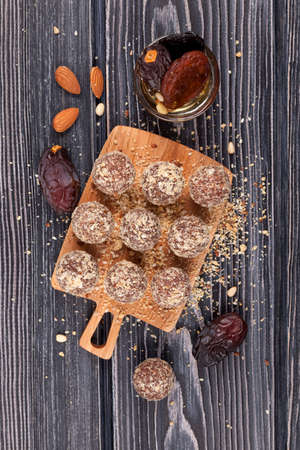 Homemade sweets on a wooden cutting board with ingredients, top view. Cooking process. Energy balls...