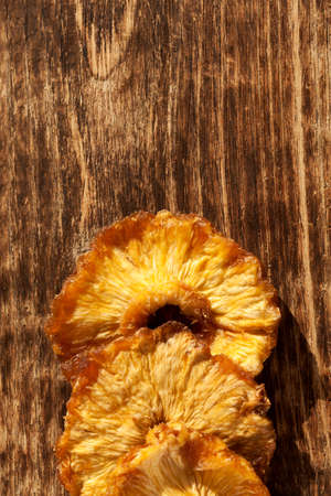 Dried pineapple. Slices on an old brown wooden board. Healthy natural sweets without added sugar. Top view, copy space.の写真素材